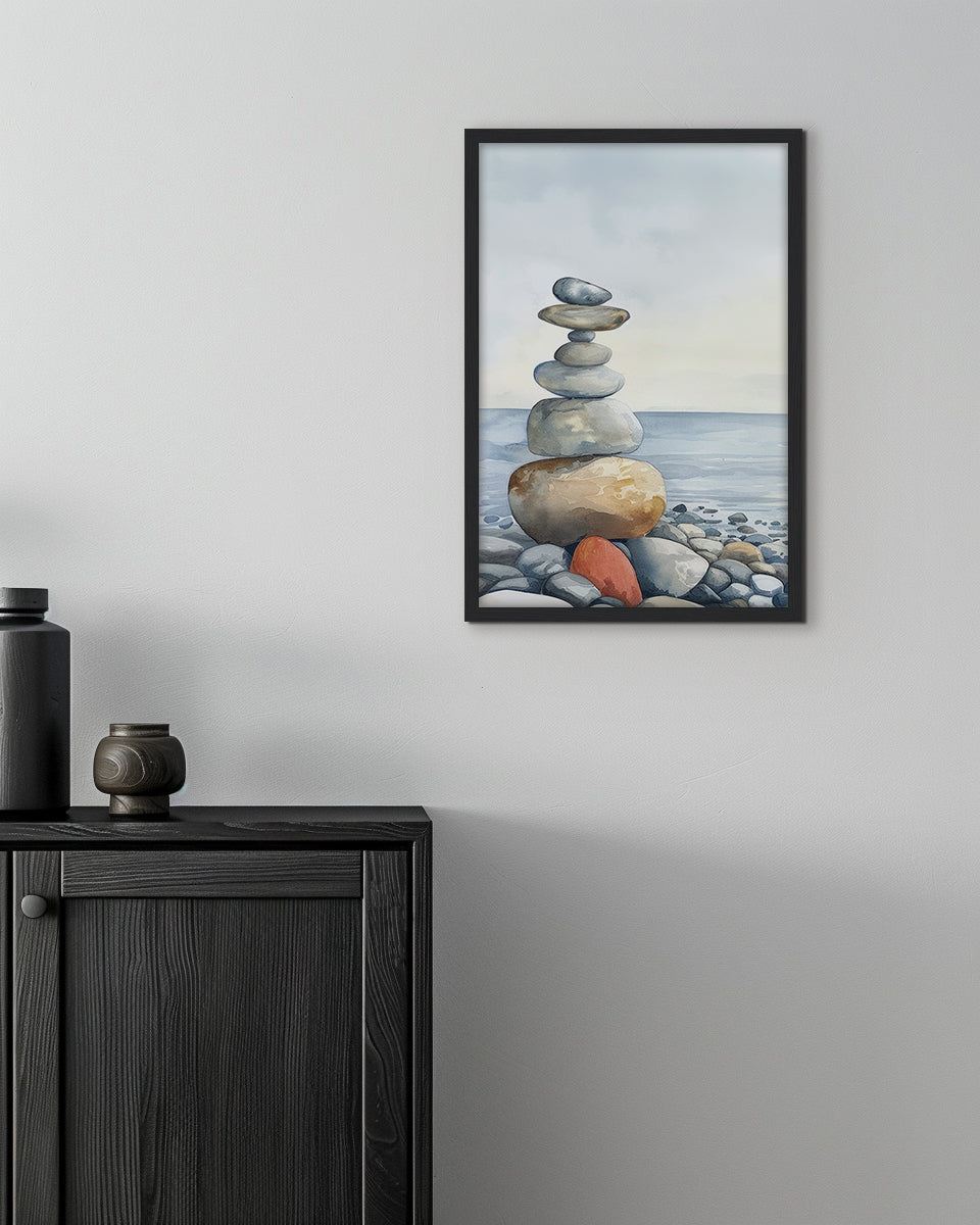 Wall art of a stack of balanced stones on a pebble beach with the ocean in the background