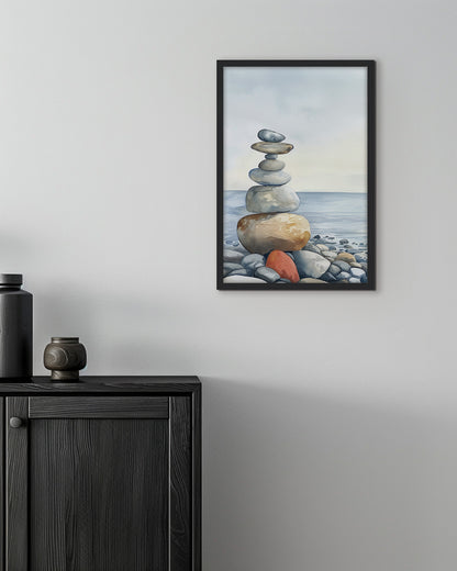 Wall art of a stack of balanced stones on a pebble beach with the ocean in the background