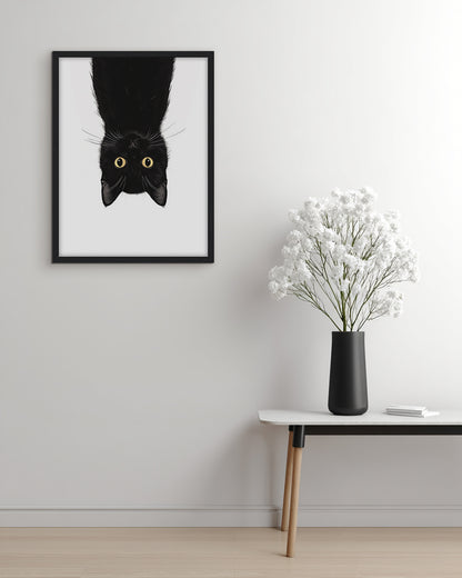 Wall art illustration of a black cat hanging upside down on a white background